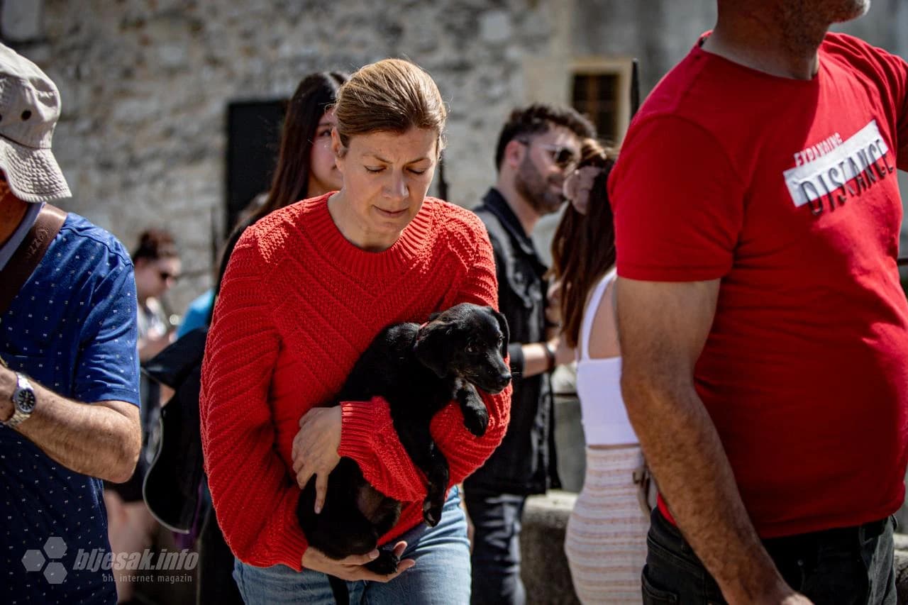 Žena nosi psa u naručju