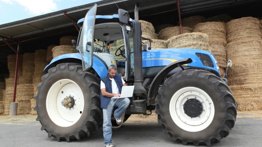 Poljoprivrednik naslonjen na traktor